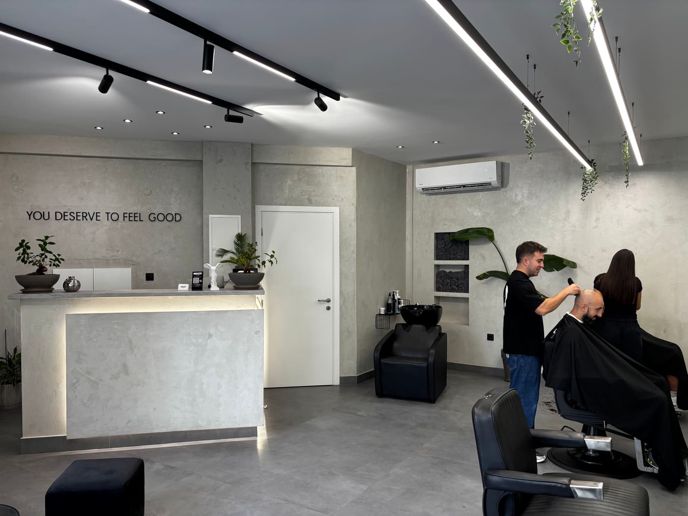 Η υποδοχή του Industry Hair με τη φράση YOU DESERVE TO FEEL GOOD στον τοίχο και το λευκό άγαλμα στον πάγκο